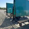 Two green banner trailers on gravel.