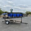 Black trailer with blue canopy and picnic tables.