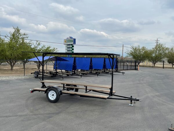 Black trailer with blue canopy and picnic tables.