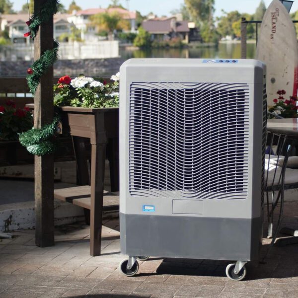 Gray evaporative cooler on wheels outdoors.