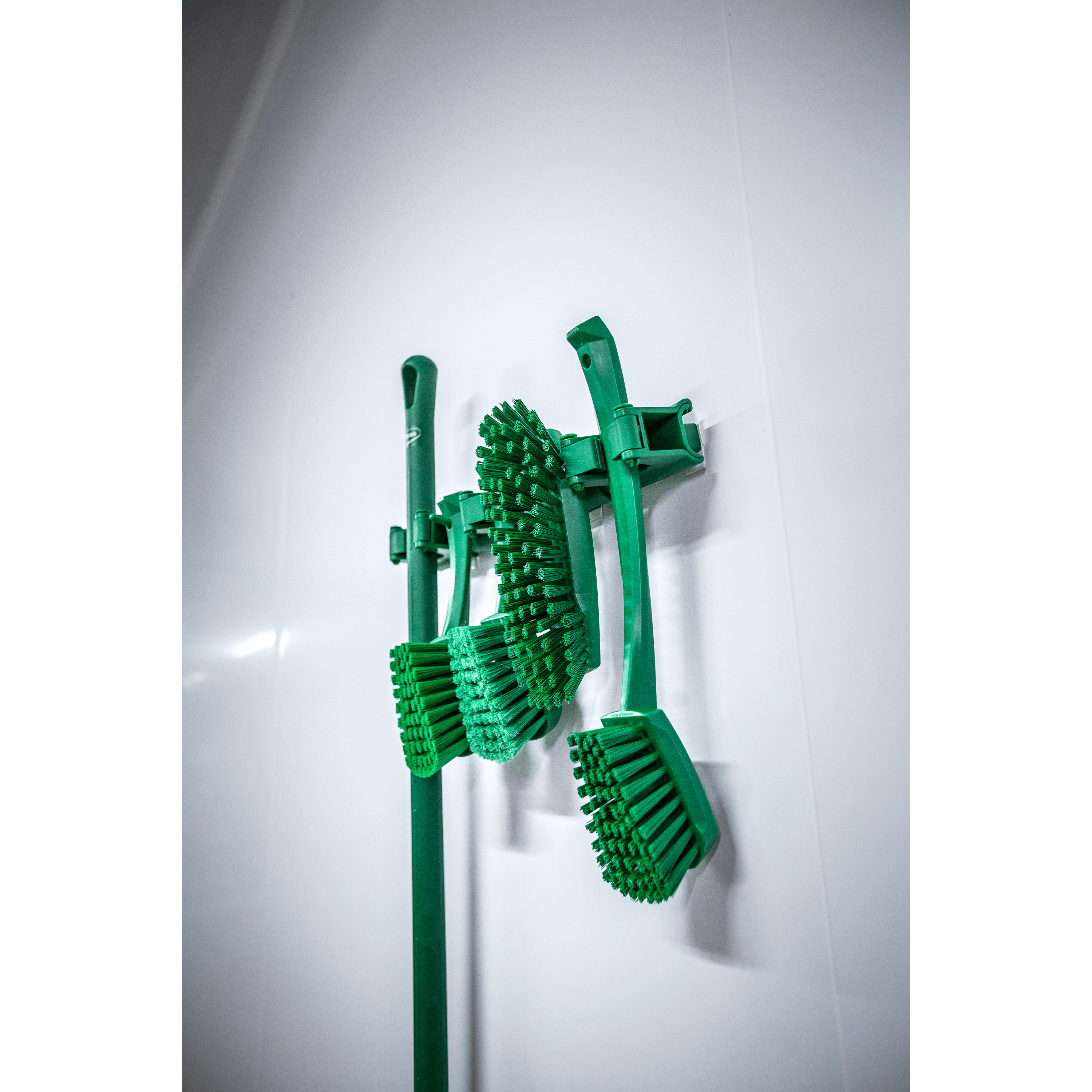 10112-2 Green cleaning brushes mounted on wall.