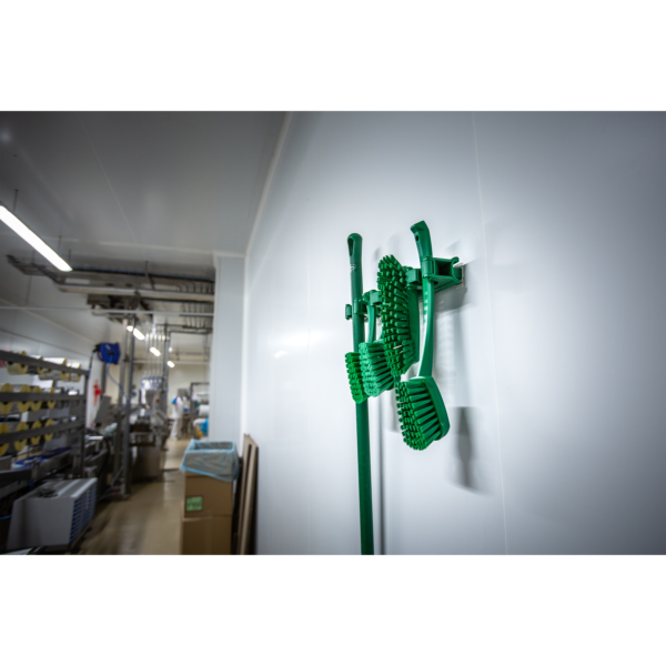 Green cleaning brushes hanging on wall.