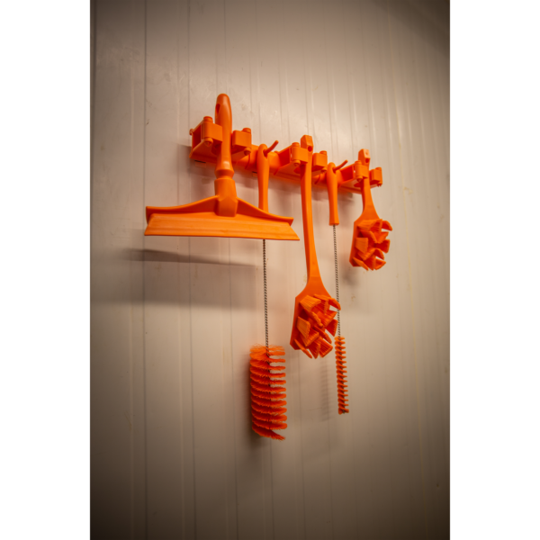 Orange cleaning brushes on white wall.