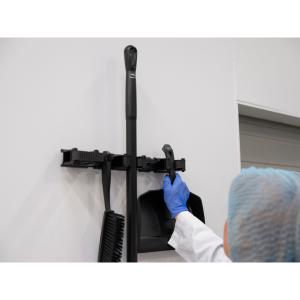 Person in gloves using a dustpan.