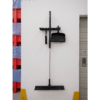 Black broom and dustpan hanging on wall.