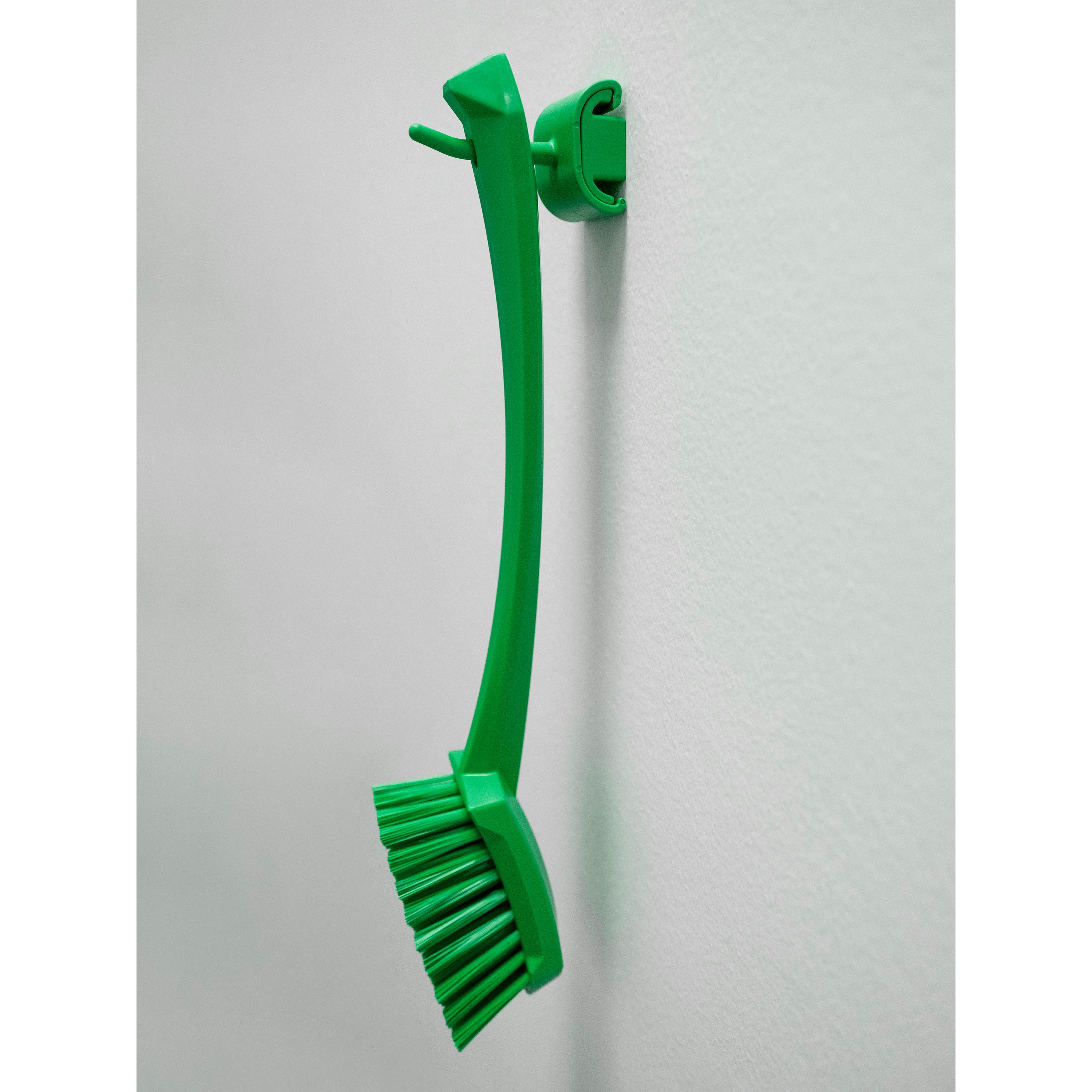 Green cleaning brush mounted on wall.