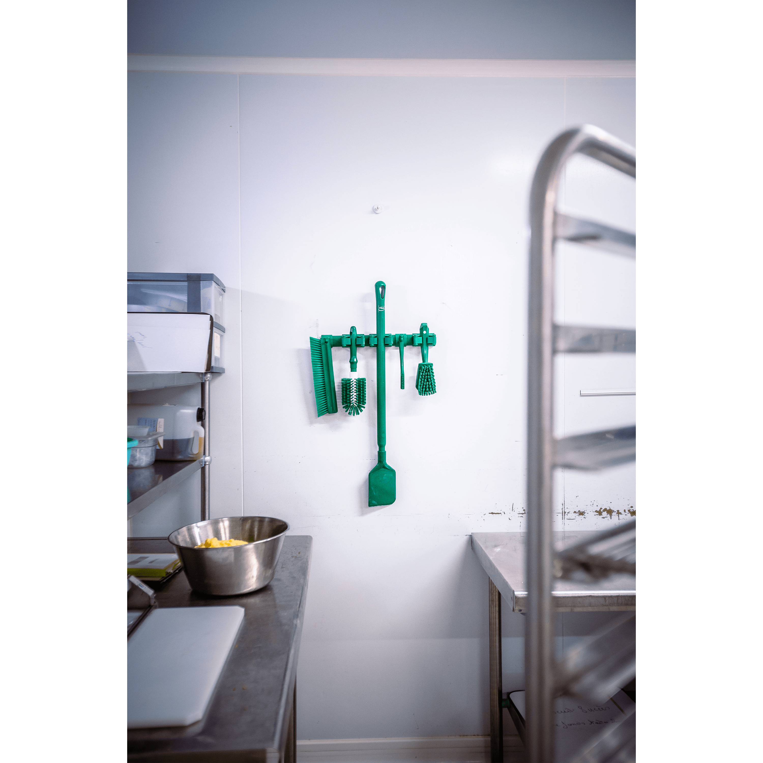Green cleaning tools hanging in kitchen.