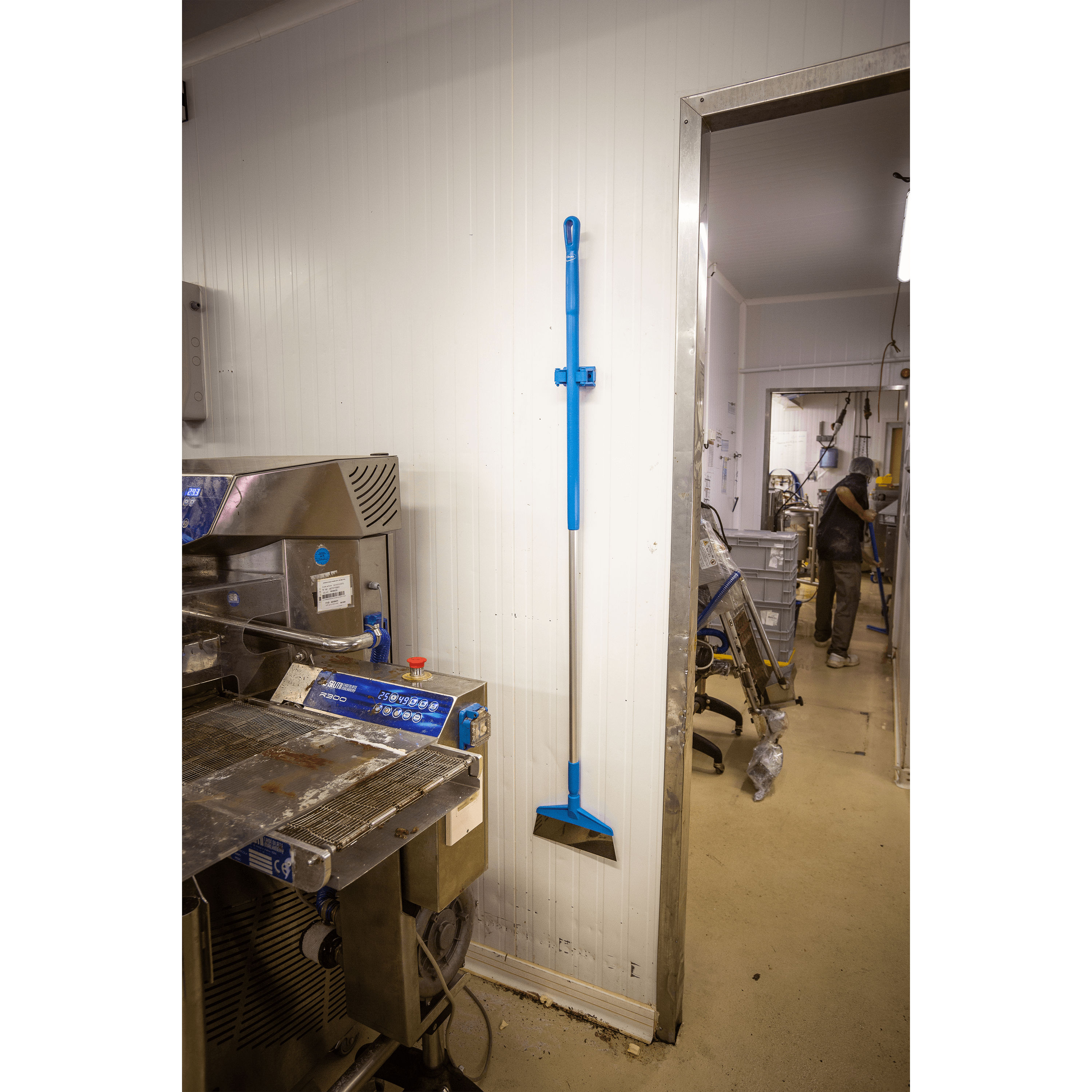 Blue broom mounted on white wall.