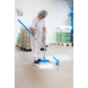 Worker sweeping floor in industrial setting.