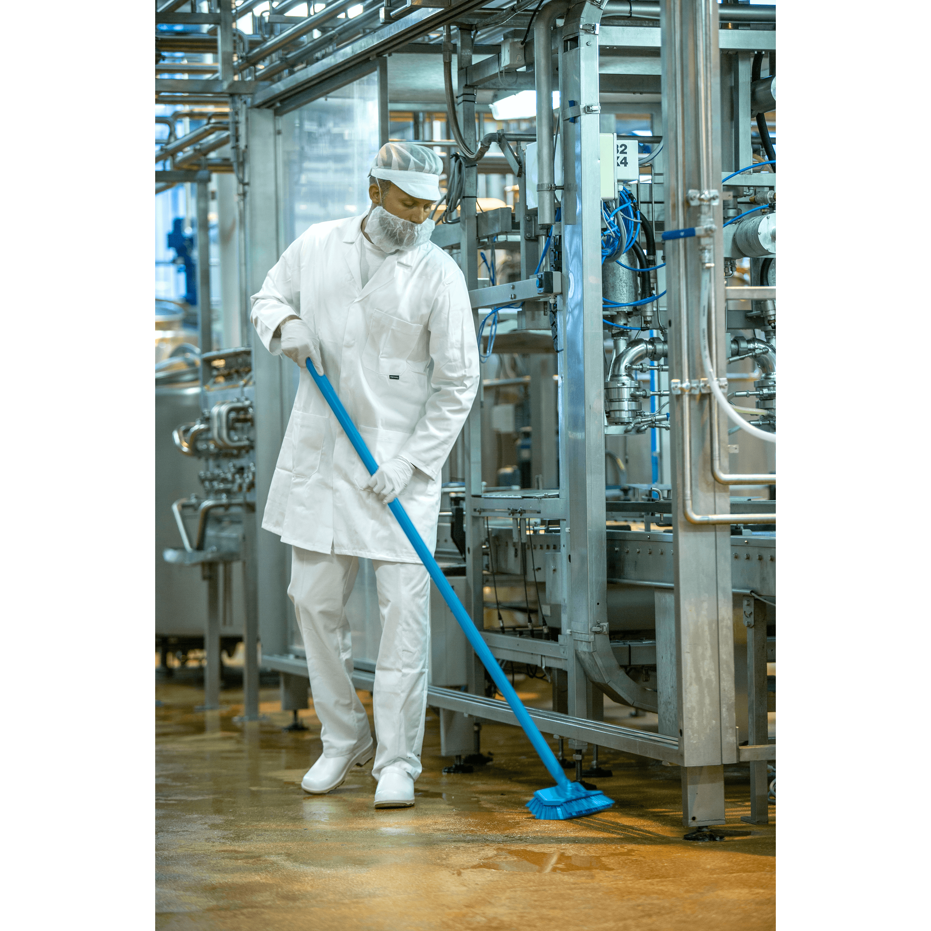 29602-4 Worker cleaning factory floor with blue brush.