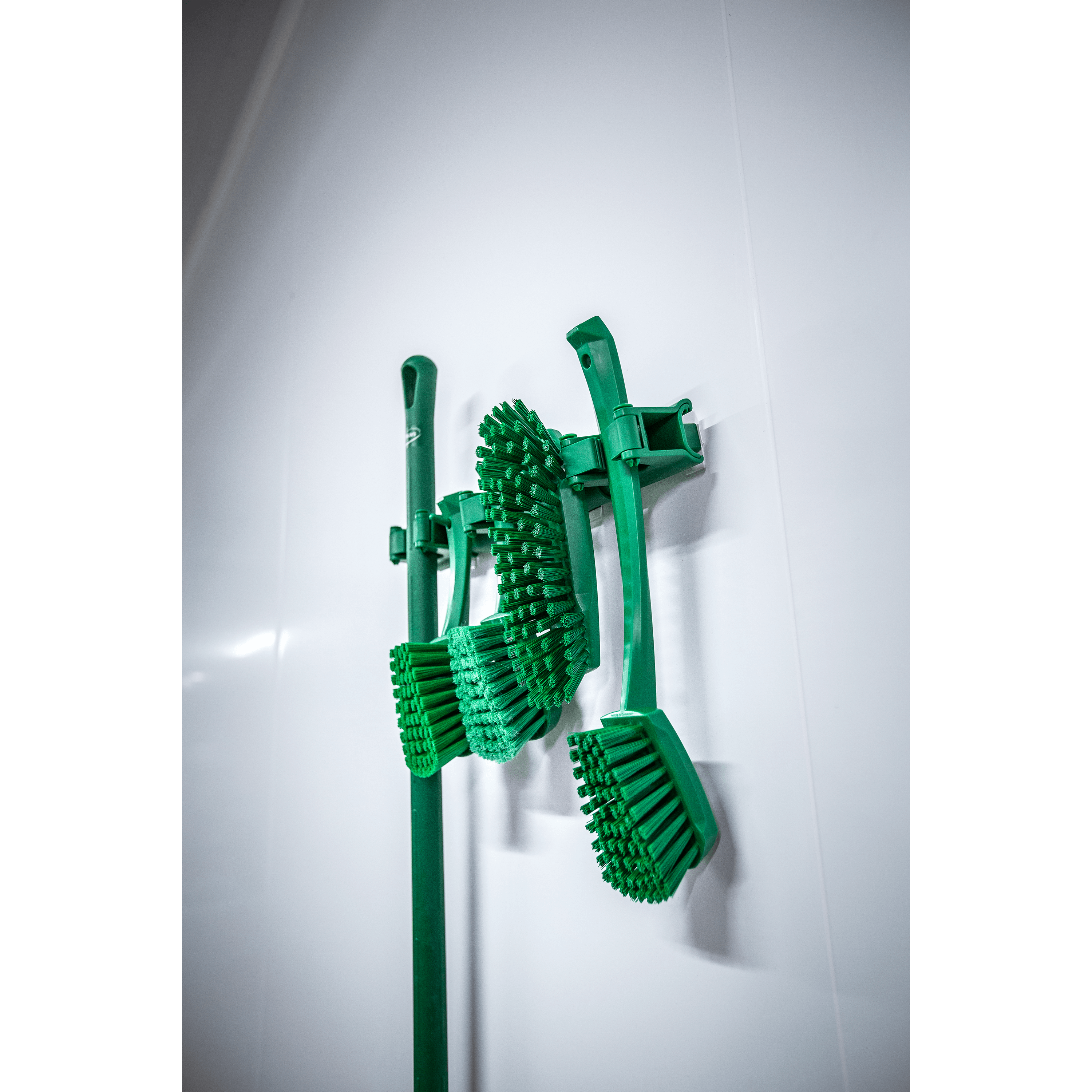 29602-5 Green cleaning brushes hanging on wall.