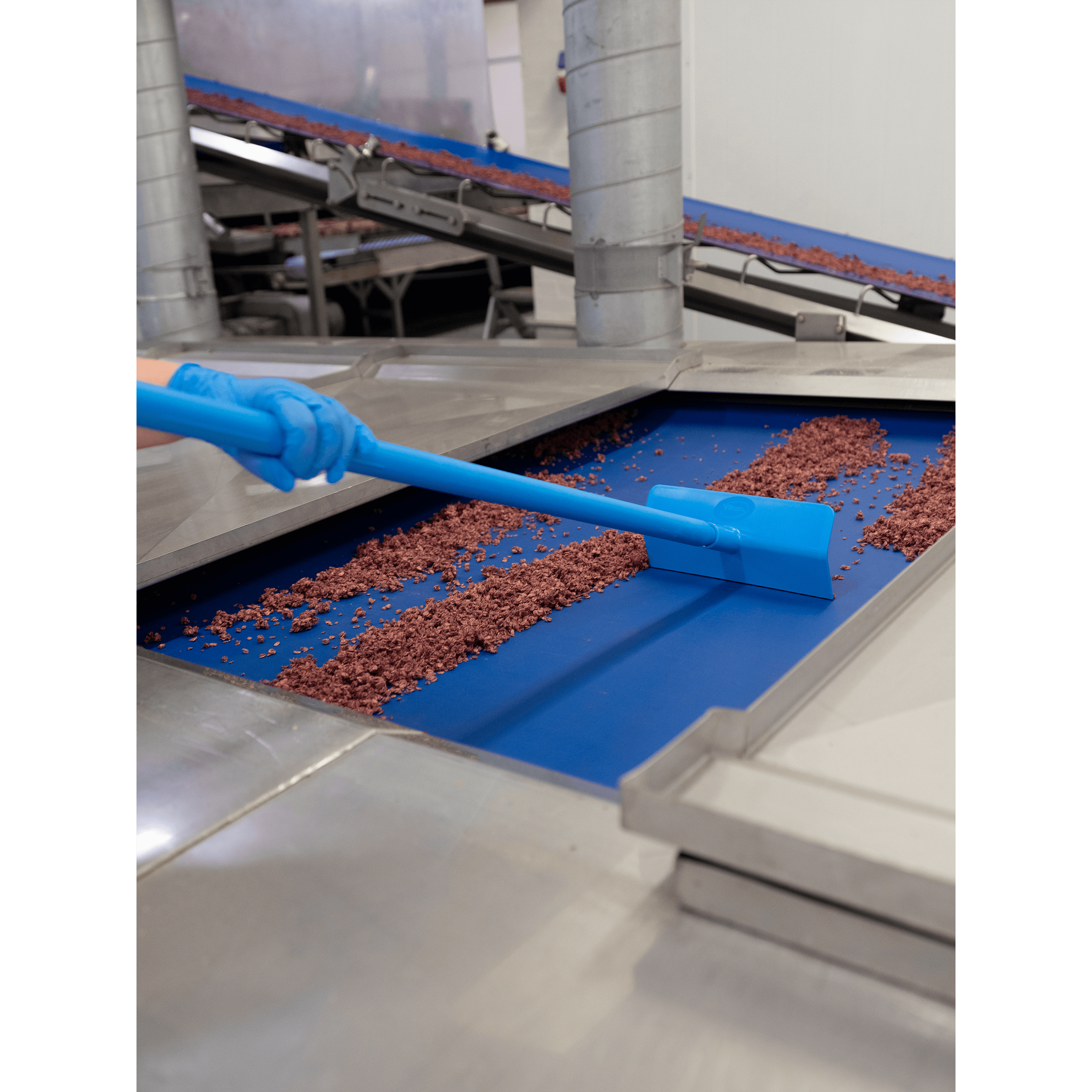 29603-5 Blue tool cleaning red granules on conveyor belt.