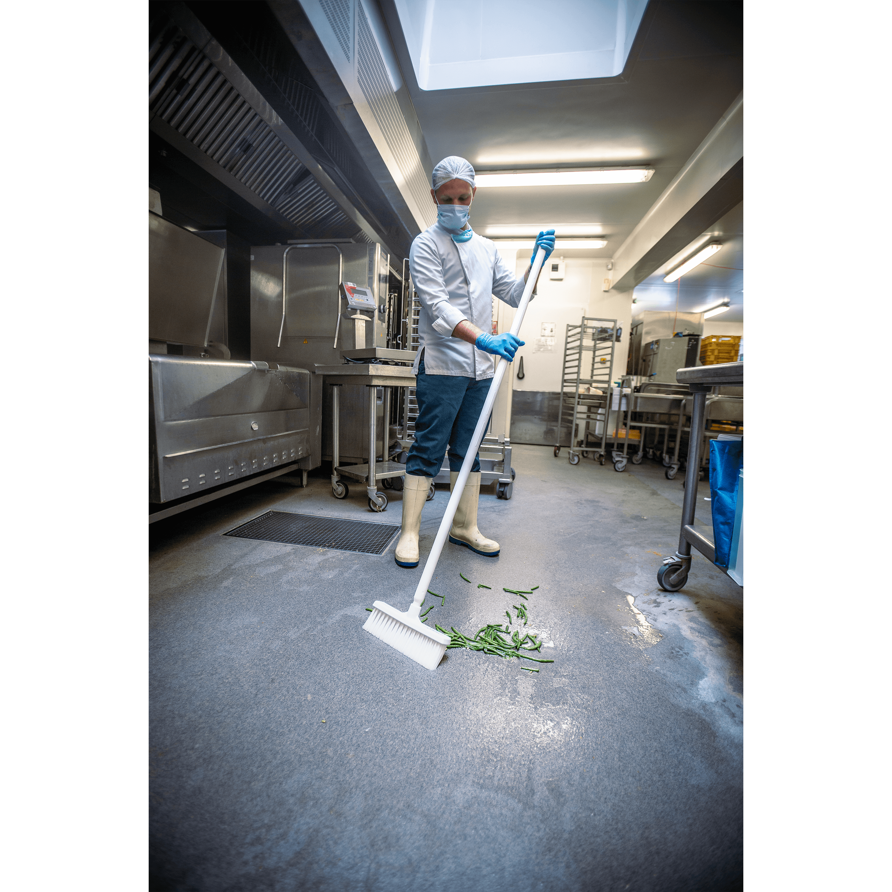 Man sweeping green beans in a kitchen.