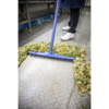 A blue broom sweeps up lettuce scraps.