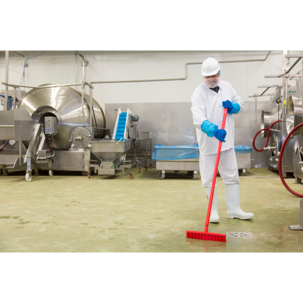 Worker sweeping a factory floor with a broom.