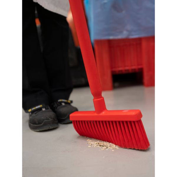 Red broom sweeping up small debris.