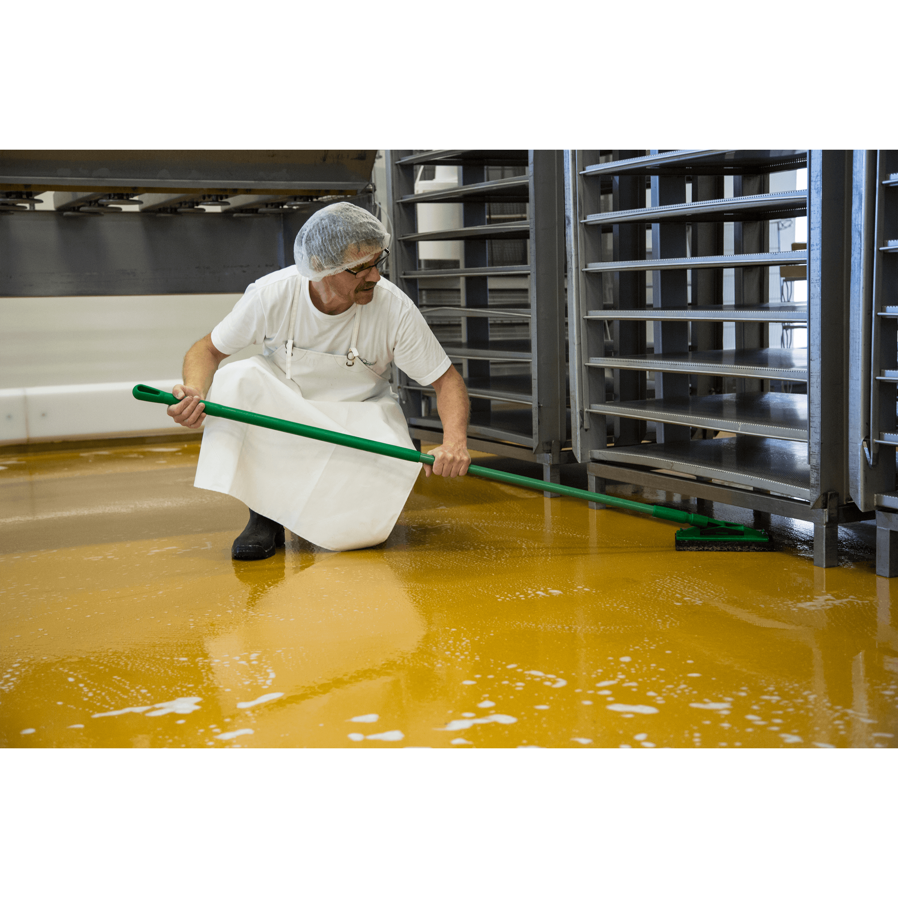 Worker mopping yellow factory floor.