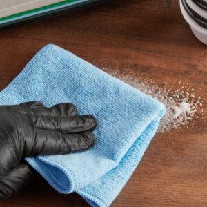 Blue microfiber cloth cleaning a wooden surface.