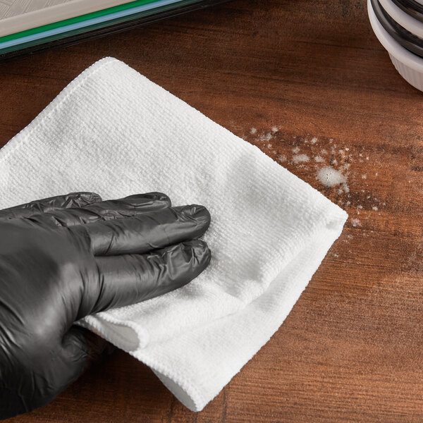 Hand in black glove wiping a table.