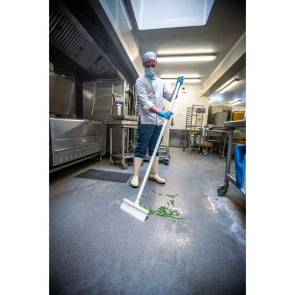 A chef sweeping green beans in a kitchen.