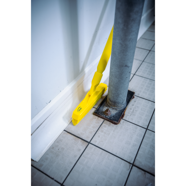 Yellow cleaning brush on tiled floor.