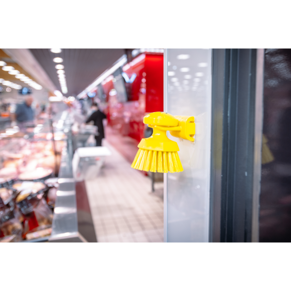 Yellow cleaning brush attached to glass door.