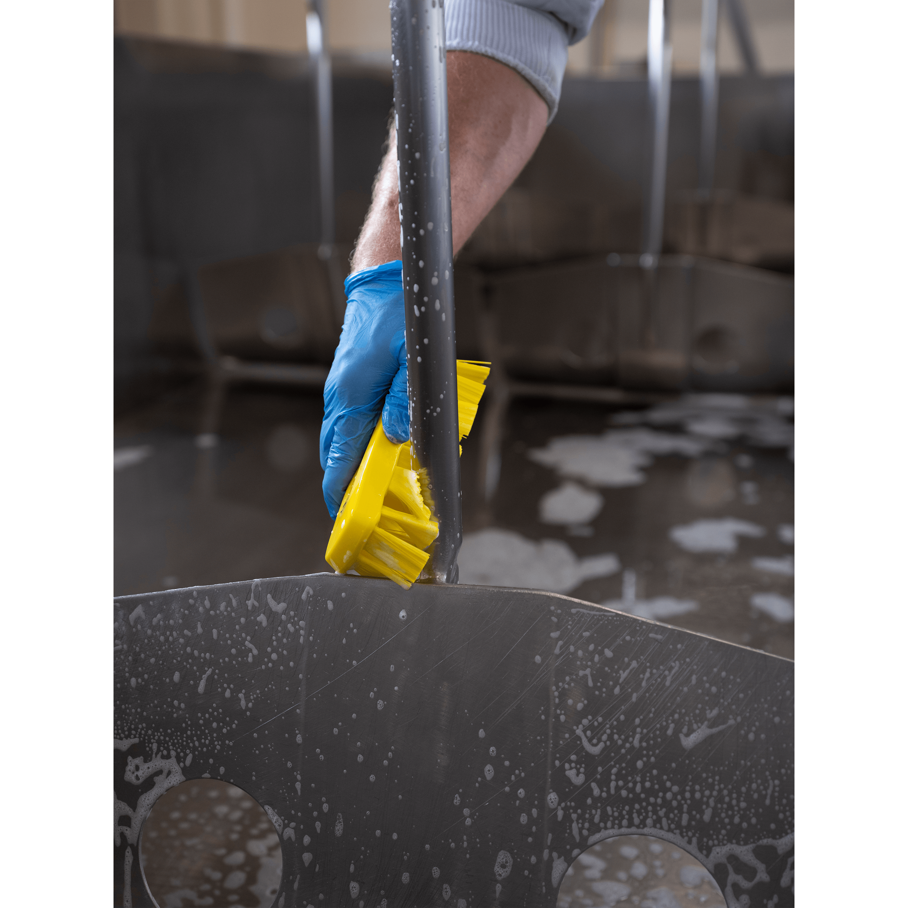 Cleaning stainless steel surface with yellow brush.