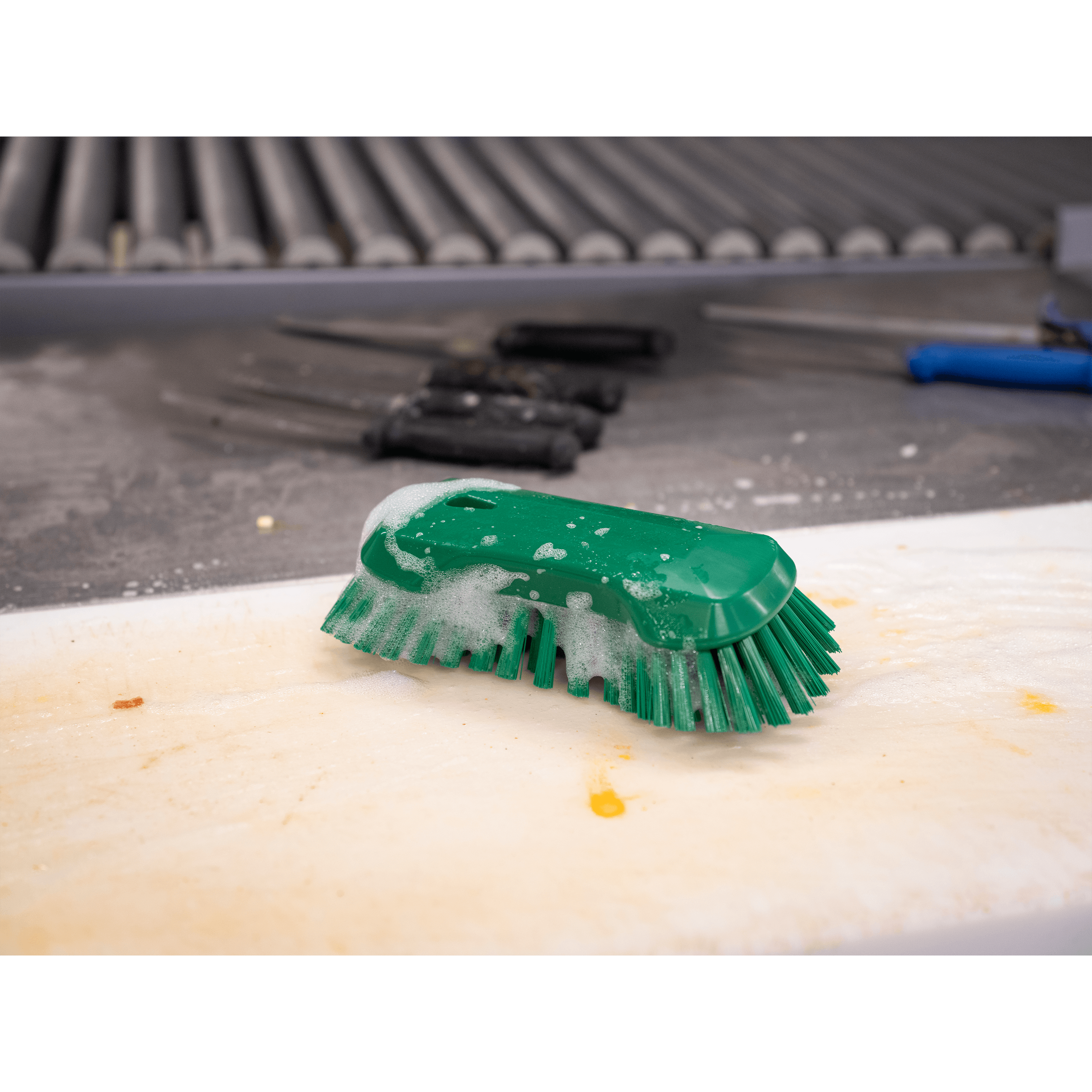 Green cleaning brush with soap on surface.