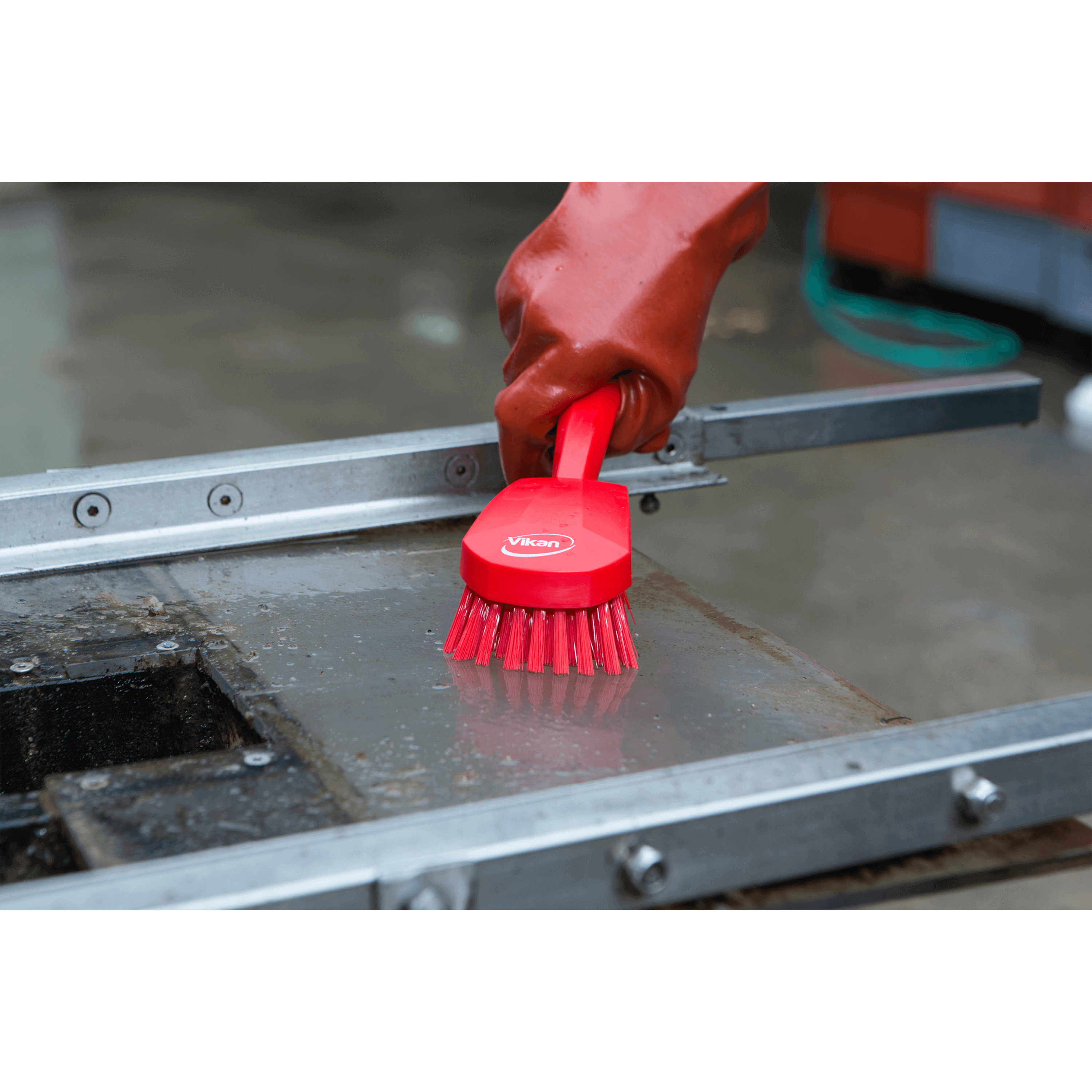Red cleaning brush scrubbing a surface.