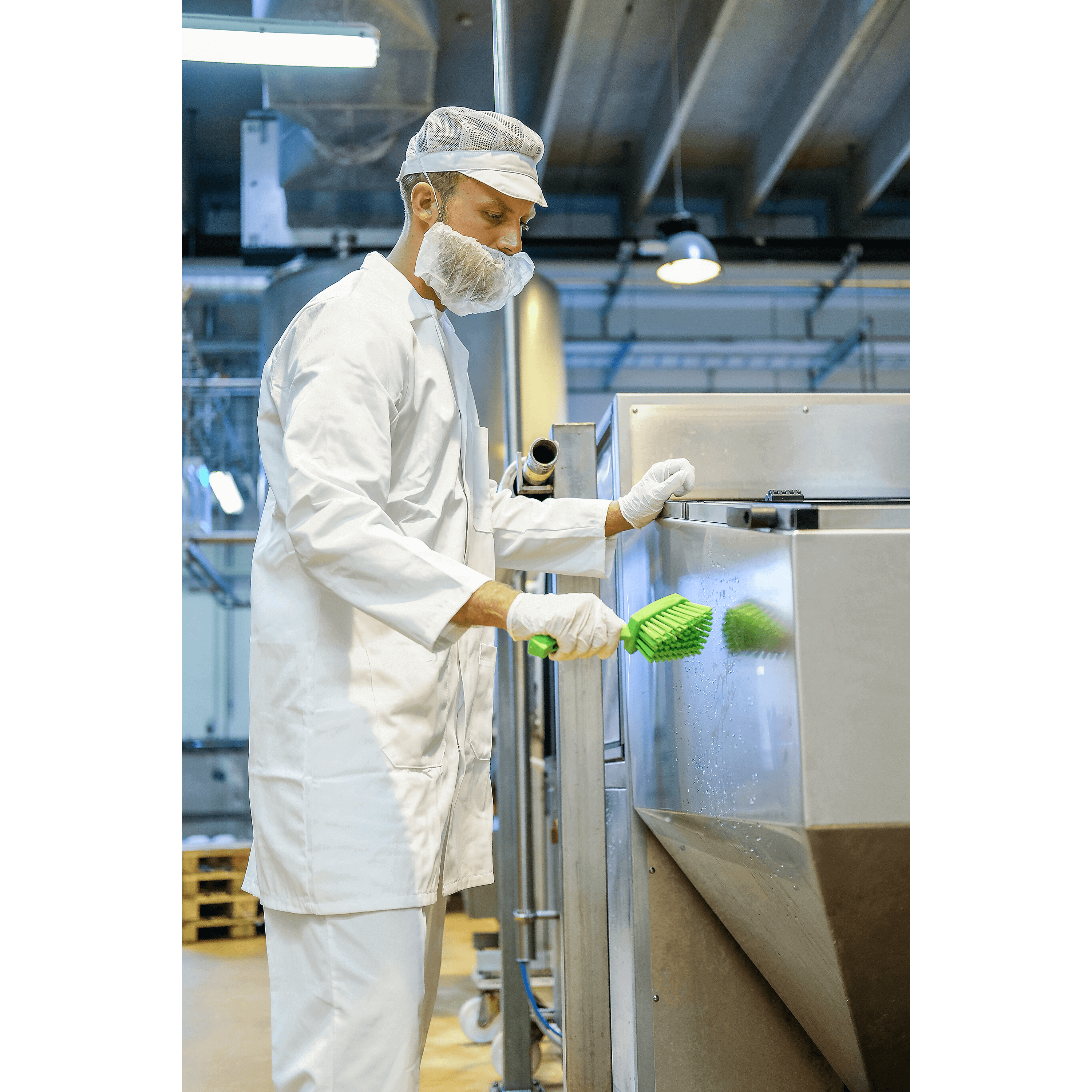 41923-3 Man in white uniform cleaning industrial equipment.